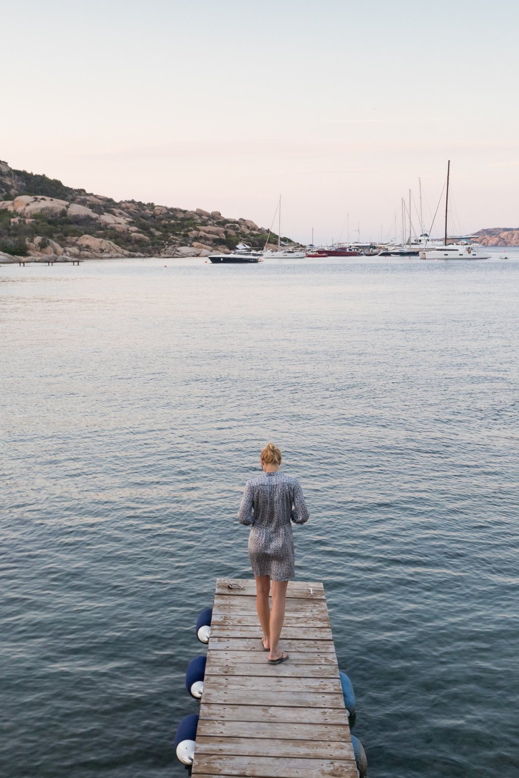 Woman Standing on Wooden Pier Enjoying Peaceful Seascape at Dusk